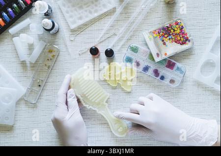 Food, Female hands in gloves hold a mold for making a comb from epoxy resin Stock Photo