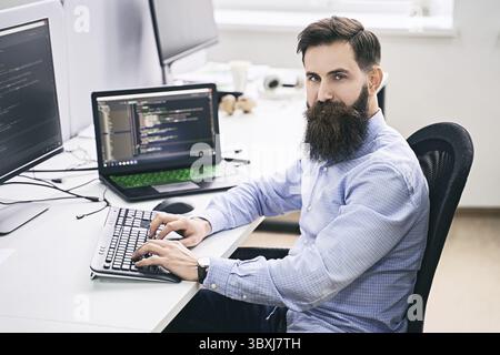 Senior developer working on computer in IT office, sitting at desk and coding, working on a project in software development company or technology star Stock Photo