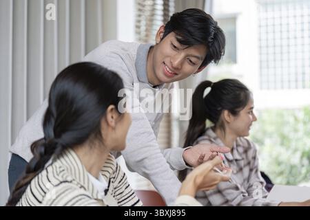 A group of students actively participating in a collaborative learning session in a bright, modern classroom environment Stock Photo