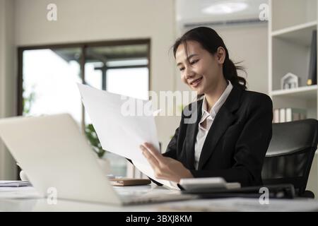 Young business woman asian or employee accounting bookkeeping documents checking financial data or marketing report working in office with laptop. Pap Stock Photo