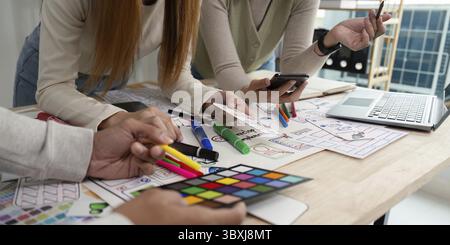 A dynamic brainstorming session with UX developers and UI designers collaborating over color palettes, wireframes, and mobile devices Stock Photo