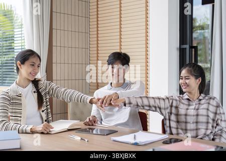Three students working together, sharing ideas, and studying in a bright, modern classroom environment Stock Photo