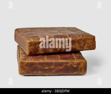 Two functional brown leather square seat cushions for comfortable rest on bench or floor arranged in stack on white background. Stylish handcrafted in Stock Photo