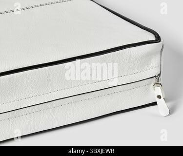 Stylish white leather briefcase featuring black piping and a secure zipper closure Stock Photo