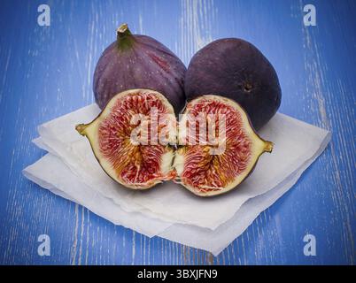 Three ripe figs on baking paper background, close up Stock Photo