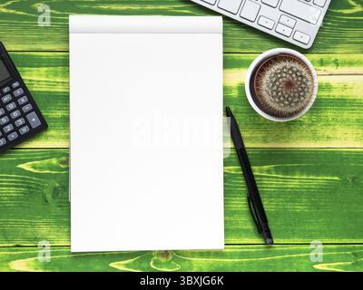Open notebook with white page, pen, calculator, computer keyboard, cactus on bright green weathered wooden table, top view Stock Photo
