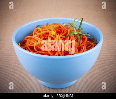 Spicy carrot salad in blue bowl on brown background Stock Photo