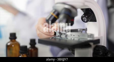 A close up view of a scientist focusing on precision analysis using a laboratory microscope, crucial for scientific research and detailed examination Stock Photo