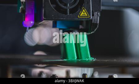 Modern 3d printer creating a green plastic object using innovative technology in a laboratory setting, showcasing the advancements in additive manufac Stock Photo
