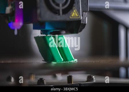 Modern 3d printer creating a green plastic object using innovative technology in a laboratory setting, showcasing the advancements in additive manufac Stock Photo