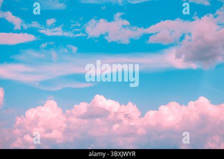 Drifting pink and white cumulus clouds float across a vibrant blue sky, crafting a dreamy and surreal atmosphere that evokes feelings of tranquility a Stock Photo