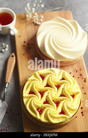 Delicious mini tarts yellow and white with nuts and custard on wooden cutting board. Assortment of delicious and colorful dessert, lemon curd tart, cr Stock Photo