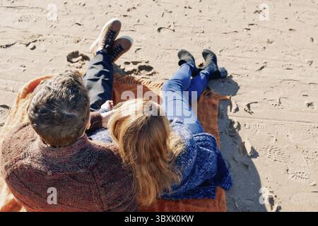 Loving couple walks on beach along sea on sunny autumn day. Weekend and lifestyle concept. Back view. Stock Photo