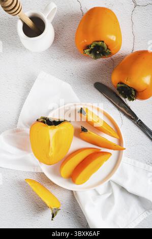Food, Plate with pieces of sweet tasty persimmon on white background top and vertical view Stock Photo