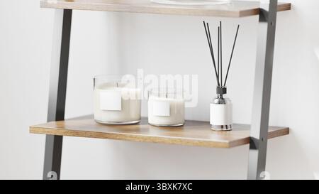 Scented candle in glass with blank label mockup with aroma reed diffuser on wooden shelf on white wall background, home aromatic candles, aromatherapy Stock Photo