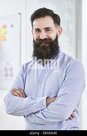 Portrait of a happy smiling bearded senior developer or manager in modern IT office Stock Photo