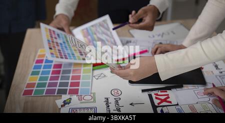 Creative UX developer and UI designer collaborating on a project, discussing color palettes and wireframes during a brainstorming session Stock Photo