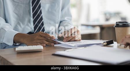 Close up of a businessman attentively examining documents at a cafe table, illustrating dedicated review and planning in an informal setting Stock Photo