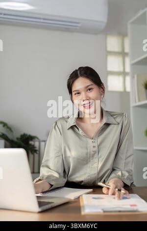 Businesswoman using laptop computer and calculator working at home with calculator document on desk, finance analysis concept Stock Photo