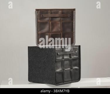Two elegant storage boxes made of leather and felt, placed on a white shelf, offer a modern and organized storage solution Stock Photo