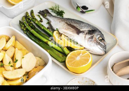 Food, He concept of a delicious dinner. raw dorado fish with asparagus, lemon and potatoes Stock Photo