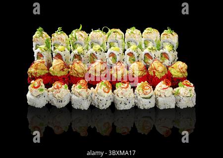 Enticing set of sushi rolls with various fillings and toppings garnished with vegetable shavings, togarashi threads and spicy sauce arranged on black Stock Photo