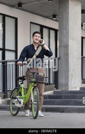 Eco friendly, Happy lifestyle asian young businessman ride bicycle go to office work at city street with bicycle in morning Stock Photo