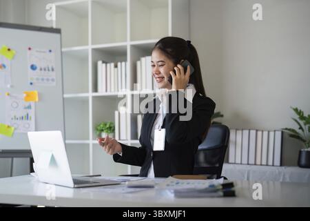 Happy confident businesswoman talking on the phone. Smiling female business person talking work using talking on the phone at office sitting at desk Stock Photo