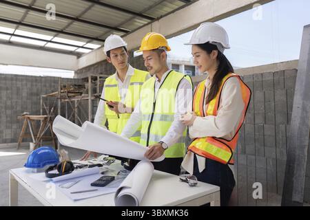 Engineers discussing construction blueprints on site, focusing on project execution and design implementation Stock Photo