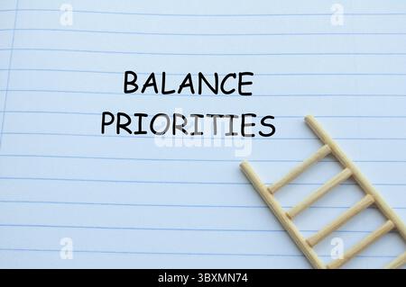Balance priorities text on notebook with wooden ladder background. Priority concept Stock Photo