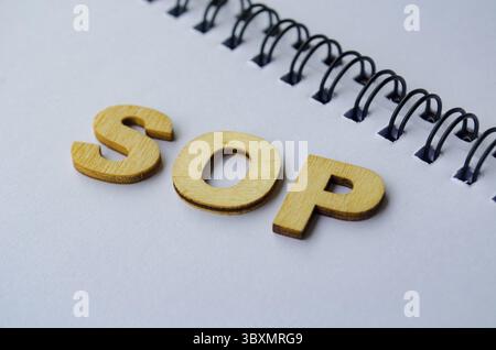 Top view of SOP wooden letters on white notepad. Standard Operating Procedure concept Stock Photo
