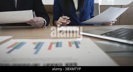 A multicultural business team engaged in analyzing financial documents while using a calculator, highlighting teamwork and analytical focus in a conte Stock Photo