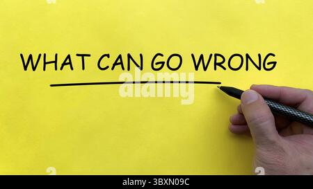 Hand writing What Can Go Wrong text on yellow cover board Stock Photo
