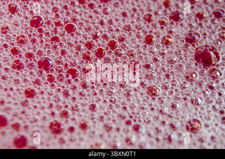 Top view of Macro shot of bubbles forming on a water surface with red background Stock Photo
