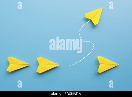 Top view of yellow paper airplane origami leaving the other yellow airplanes on blue background with customizable space for text Stock Photo