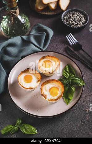 Food, Baked egg and bacon rolls with basil on a plate on a table vertical view Stock Photo