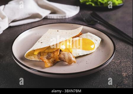 Food, Quesadilla with fried egg, bacon and cheese on a plate on the table Stock Photo