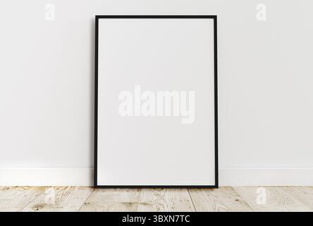Empty thin black frame on light wooden floor with white wall behind it. Empty poster frame mockup. Empty picture frame mockup. Blank photo frame Stock Photo