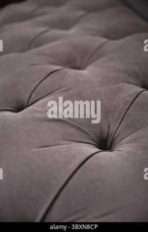 Grey upholstery of a very soft sofa with buttons made of thick fabric. Close-up Stock Photo