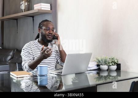 Professional man working remote from home with technology. African American male has a business meeting on an audio call phone Stock Photo