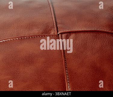 Background of stitched square patches of copper-coloured genuine leather. Handcrafted furniture upholstery. Textured pattern Stock Photo