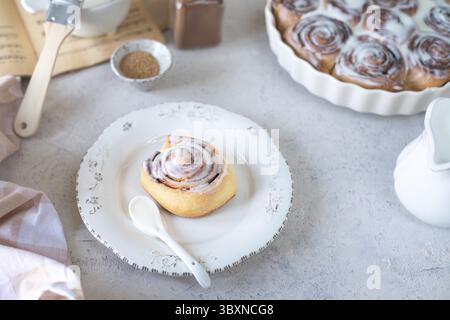 Food, Homemade cinnamon rolls in glaze on a white plate, stone background Stock Photo