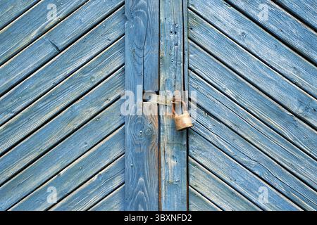 Old padlock on a weathered retro blue wooden door. Textured background Stock Photo