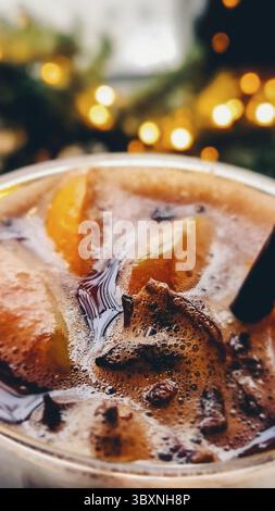 Christmas mulled wine on blurred background of bright lights. Traditional New Year's hot drink made from red wine, orange, cinnamon, apples and star a Stock Photo