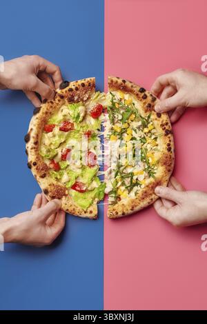 Four hands taking slices of delicious pizza with different toppings on a vibrant two-tone background Stock Photo