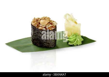 Gunkan maki sushi with eel seasoned with spicy sauce and sesame, presented with wasabi and pickled ginger on bamboo leaf, isolated on white background Stock Photo