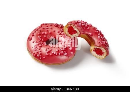 Vibrant red glazed soft donuts with sweet and sour berry jelly filling sprinkled with sugared berry crumbs, isolated on white background. Handcrafted Stock Photo