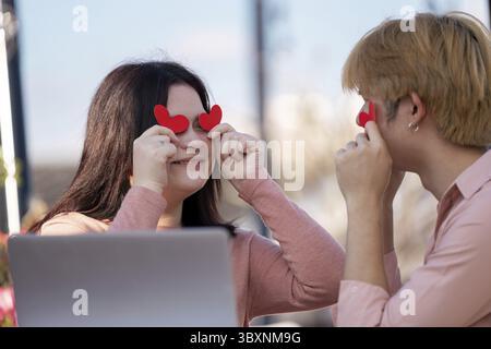 Couple celebrating valentine's day with heart-shaped props in outdoor romantic setting capturing joyful moments of love Stock Photo