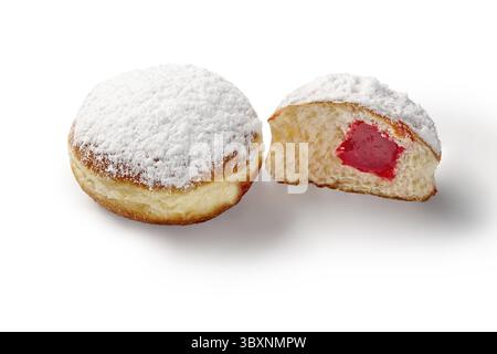Two fresh jelly doughnuts, one cut open showing the red filling, covered in powdered sugar, isolated on white Stock Photo