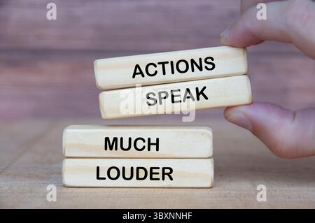 Hand holding wooden blocks with Action Speak Much Louder text on wooden blocks Stock Photo
